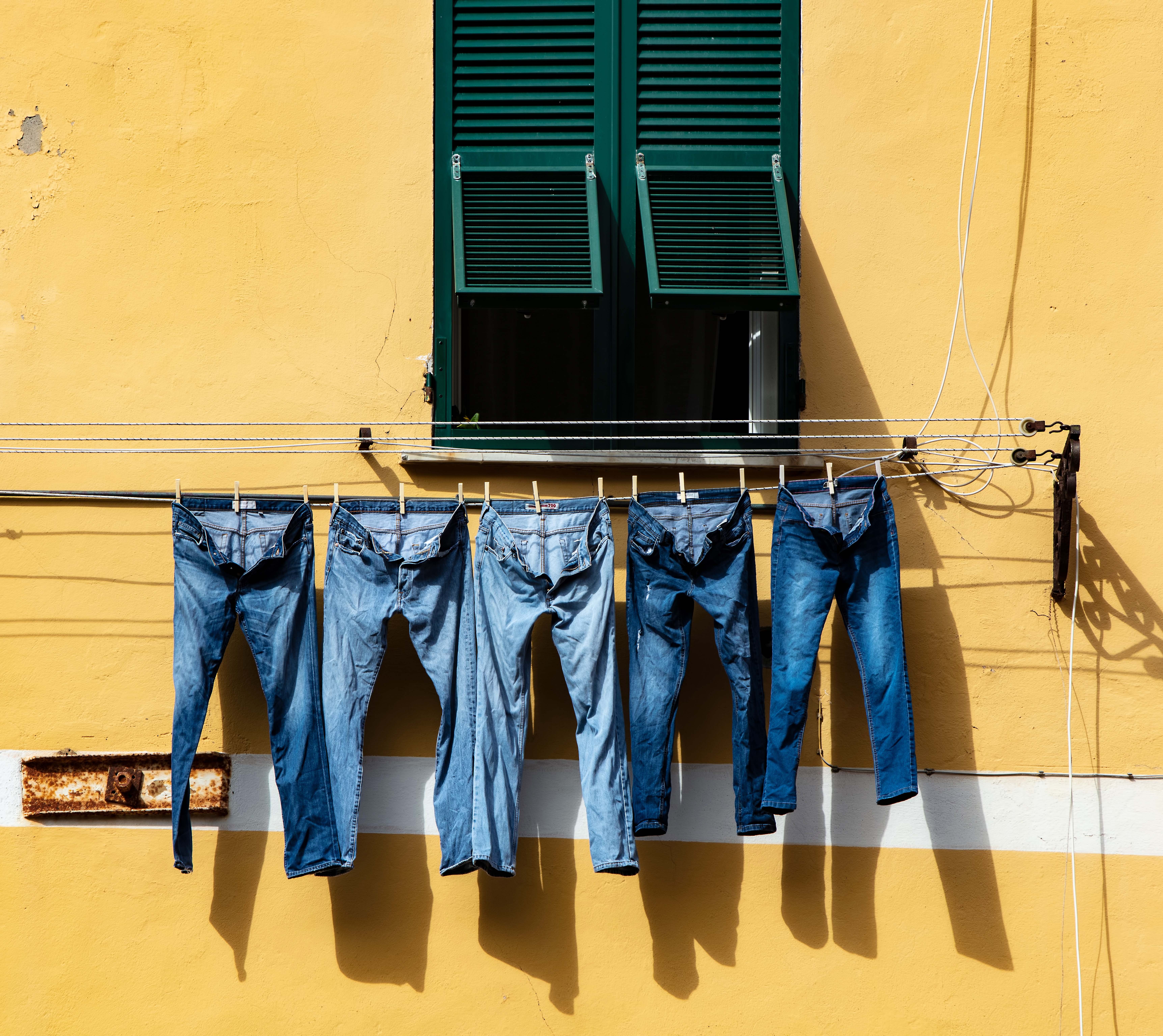 Jeans hanging to dry outside a window.